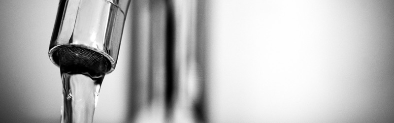 Vand fra vandhane løber ned i et glas